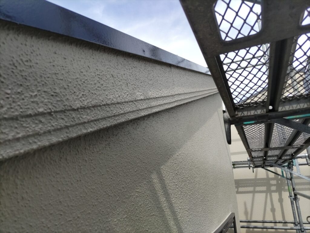 金属笠木の下に続く凹凸のある外壁