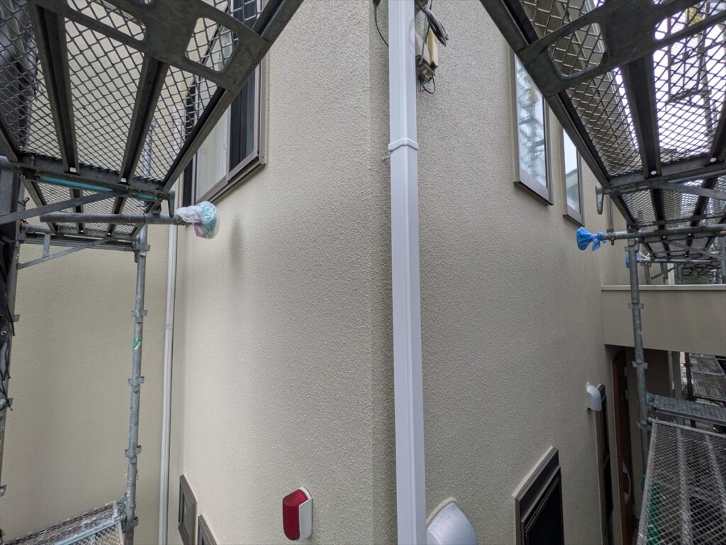 白い縦樋、窓、換気フードが並ぶ建物の角