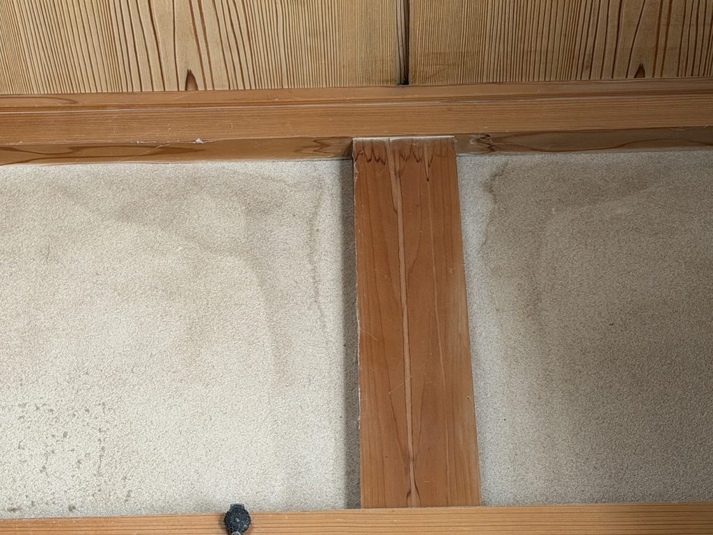 S__4169749_0 | 外壁塗装は神奈川県横浜市の塗装職人 Vertical wooden support beam intersecting a wood-paneled ceiling with horizontal planks and beige carpeting below.