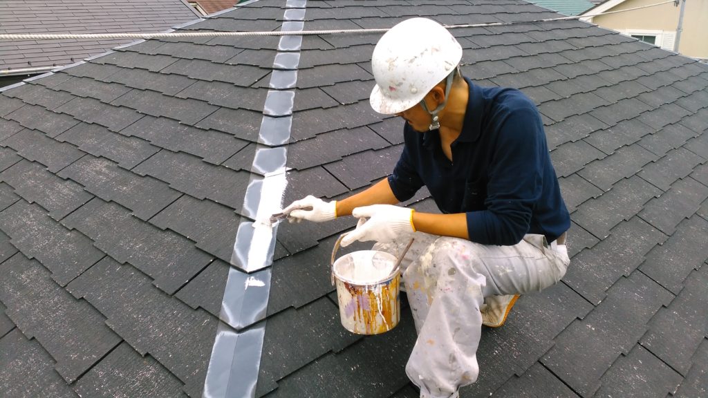株式会社塗装職人 ストレート屋根の棟板金を刷毛で塗っている職人